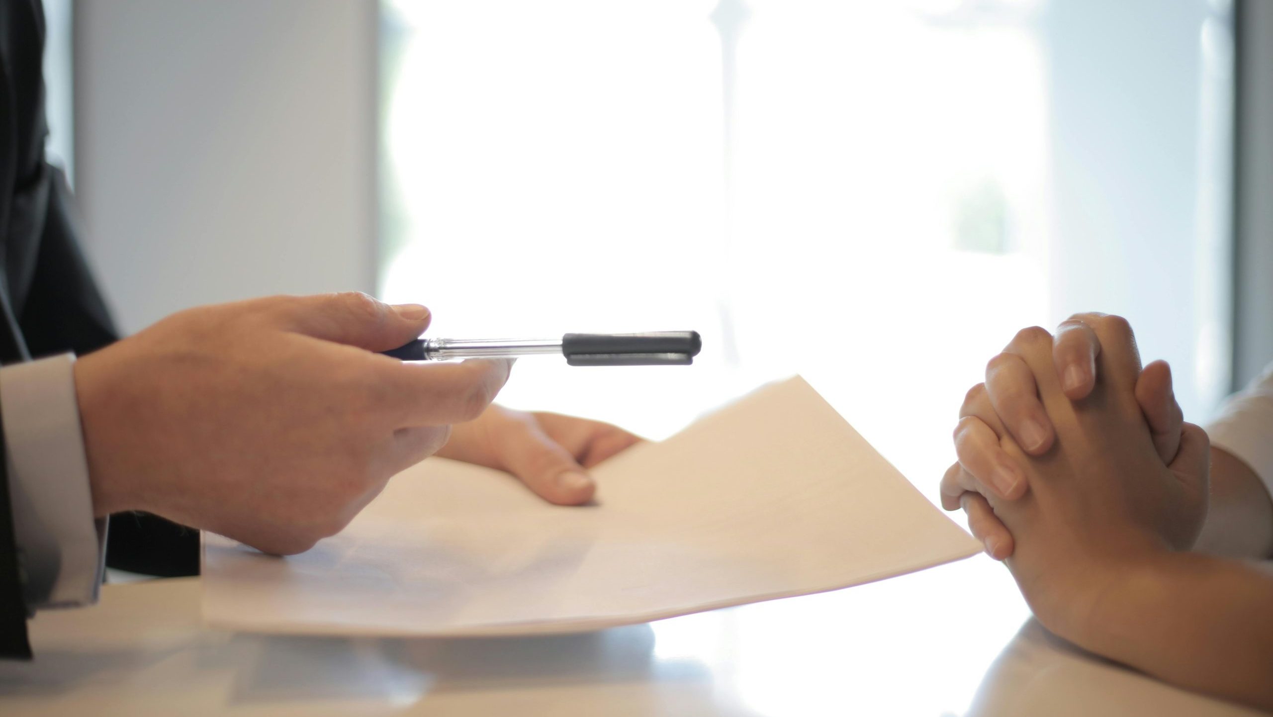 Close-up of a contract signing with hands over documents. Professional business interaction.